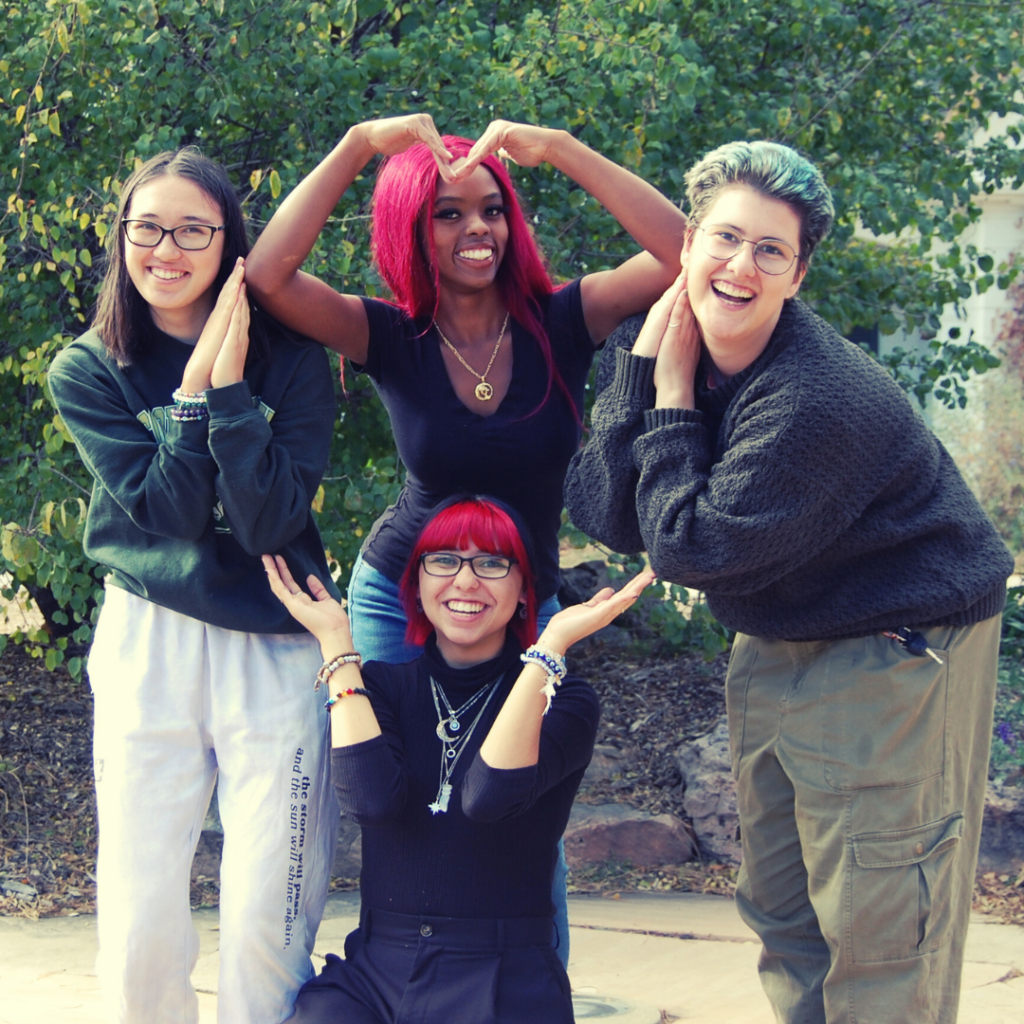 Students playfully pose to create a large heart using their arms and bodies