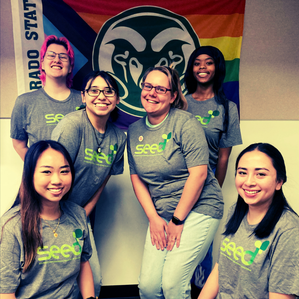 Student educators pose in front of a Colorado State University Pride flag